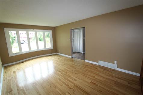 Large living room with hardwood flooring and bay window.