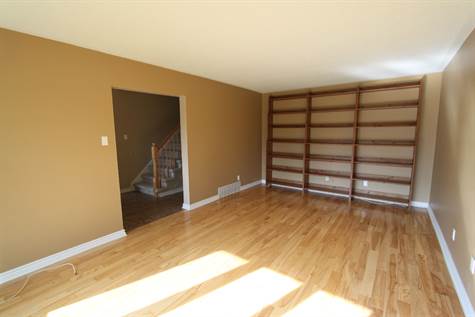 Living room with built-in shelves and hardwood flooring.